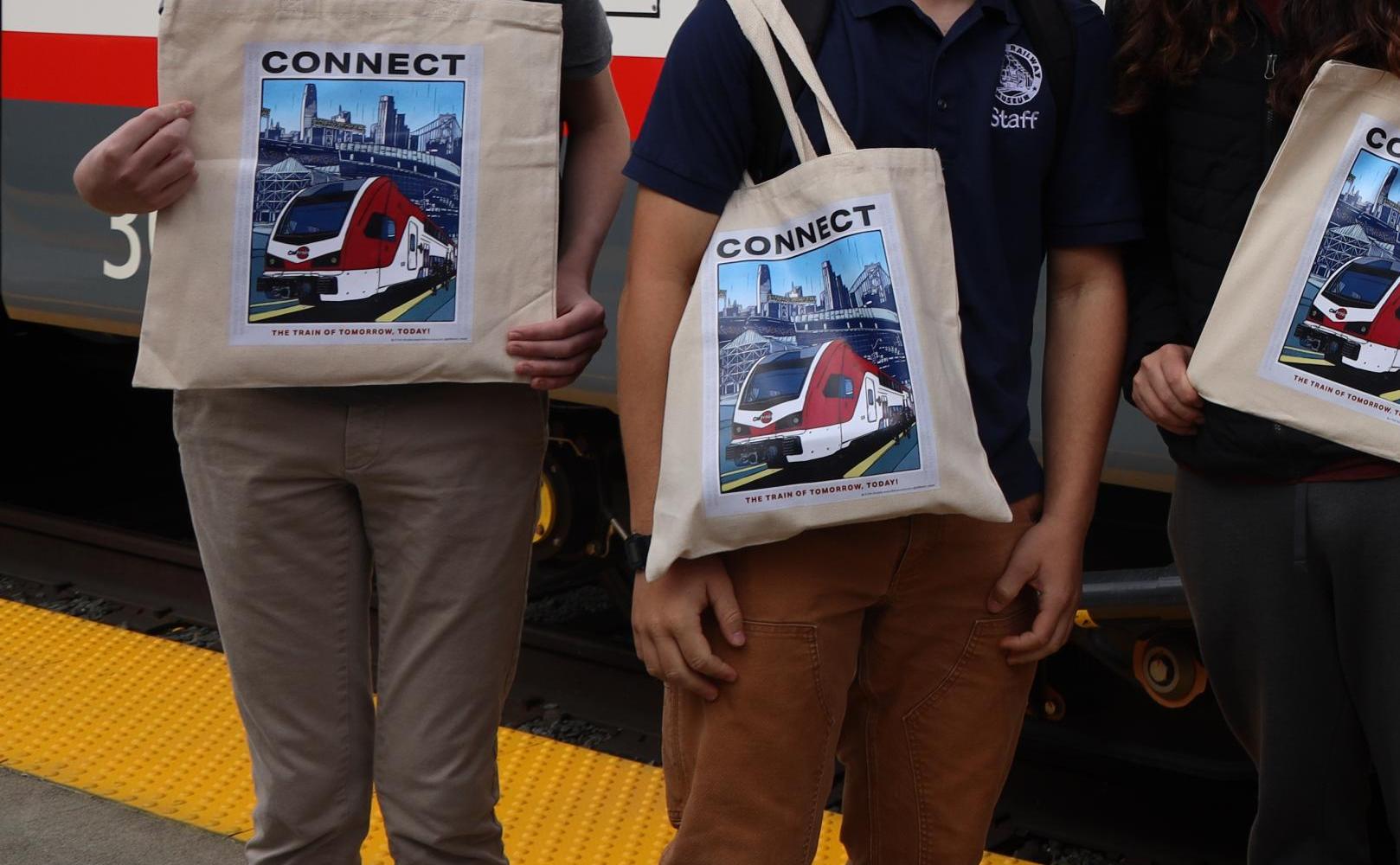 Group of young people posing in front of EMU with their tote bags